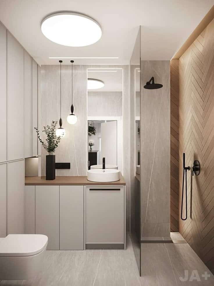 Modern bathroom with sleek vanity, round mirror, pendant lights, and rainfall shower. Minimalist design.