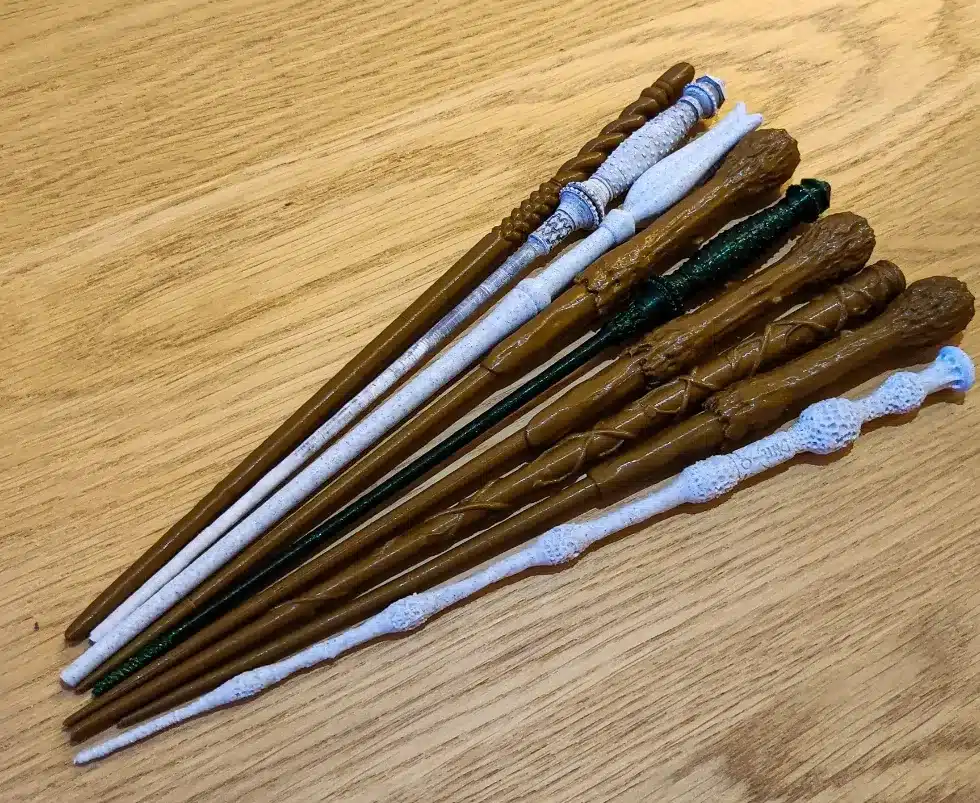 A collection of intricately designed wizard wands arranged on a wooden surface, showcasing detailed craftsmanship and unique patterns.