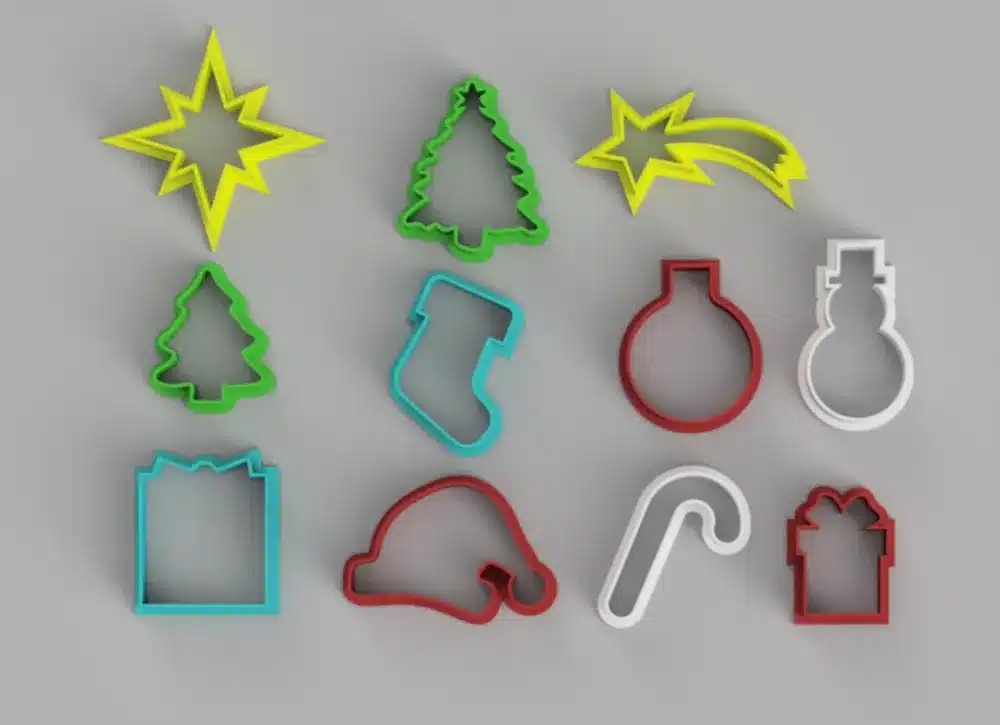 Colorful Christmas-themed cookie cutters on a gray background, including star, tree, stocking, and ornament shapes.