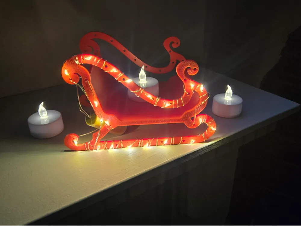 2024-12-01_724f653df1069 Festive red sleigh covered in warm white fairy lights, surrounded by LED tea light candles on a shelf, creating a cozy holiday atmosphere. | Sky Rye Design Festive red sleigh covered in warm white fairy lights, surrounded by LED tea light candles on a shelf, creating a cozy holiday atmosphere.