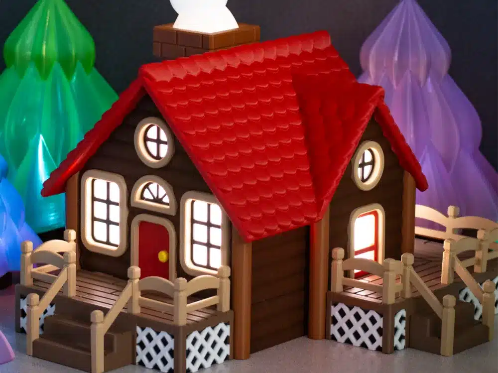 Toy log cabin with red roof, glowing windows, and surrounding colorful plastic trees, creating a cozy, whimsical scene.