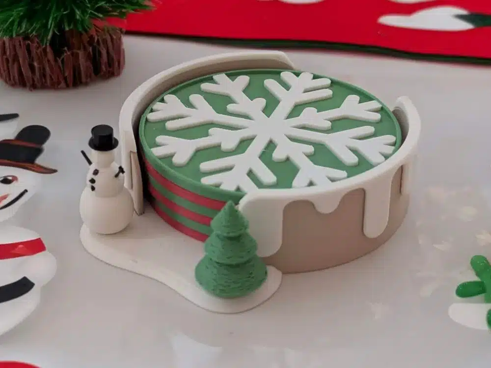 2024-12-22_f17adc329d06d Festive holiday decor featuring a snowflake coaster holder, a small snowman, and a green tree on a table with Christmas-themed items. | Sky Rye Design Festive holiday decor featuring a snowflake coaster holder, a small snowman, and a green tree on a table with Christmas-themed items.