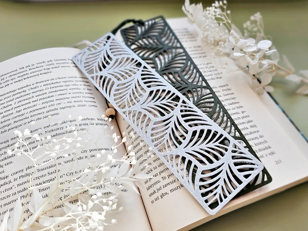Decorative laser-cut bookmarks on an open book with delicate white flowers, creating a serene reading atmosphere.
