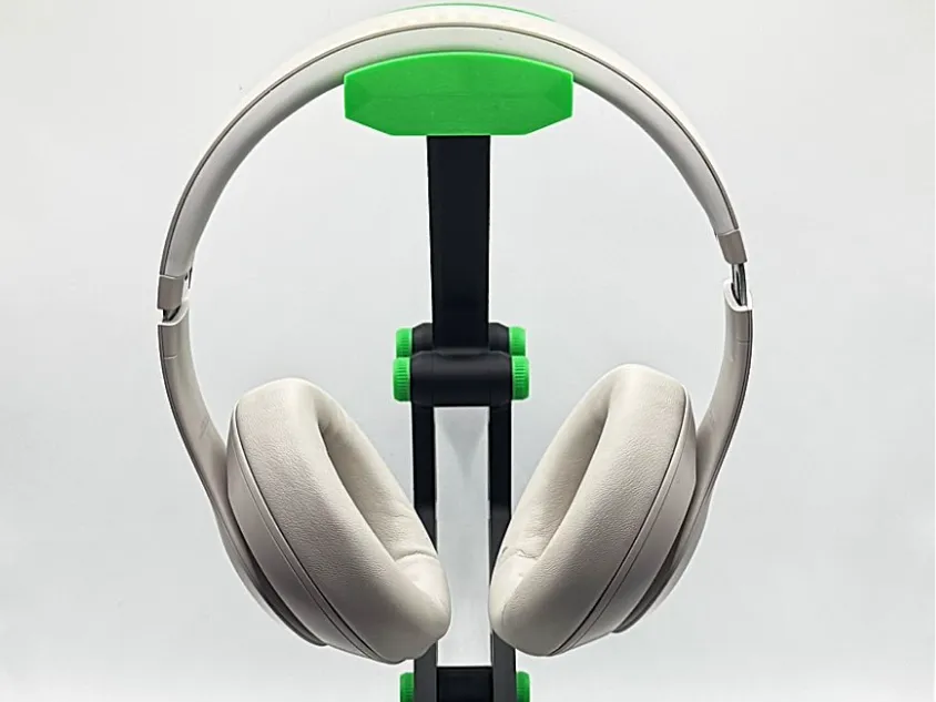 Sleek white over-ear headphones on a black and green stand, showcasing modern design and comfort. Perfect for music lovers and gamers.