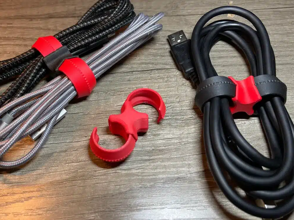 Organized cables with red and black cable ties on a wooden surface, showcasing efficient cable management solutions.