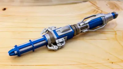Futuristic blue and silver tool with intricate design resting on a wooden surface, resembling a sci-fi gadget or prop.