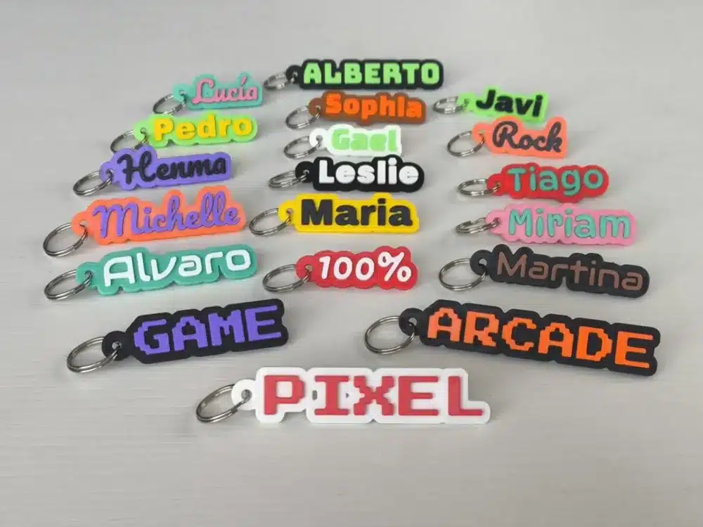 2025-04-10_a973a0f2e8cb2 Colorful name keychains with various designs on a light surface, including words like GAME and PIXEL. | Sky Rye Design Colorful name keychains with various designs on a light surface, including words like GAME and PIXEL.