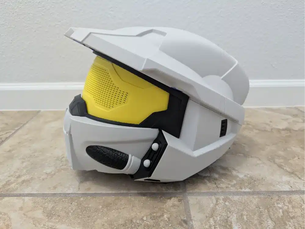 Futuristic white and yellow sci-fi helmet on a tiled floor, showcasing sleek and modern design, ideal for cosplay or display.