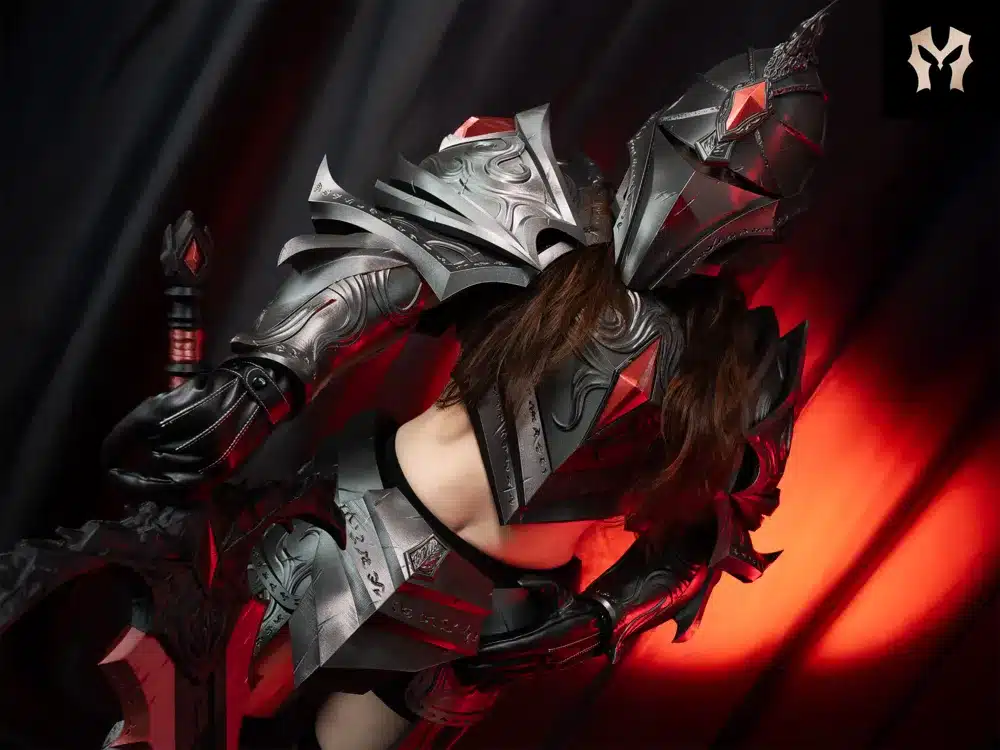 Person in elaborate fantasy armor with intricate designs and red accents, posed against a dramatic red and black backdrop.