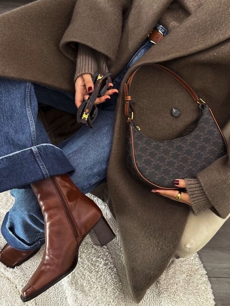 Stylish outfit featuring a brown coat, jeans, brown leather boots, designer handbag, and sunglasses for a chic autumn look.