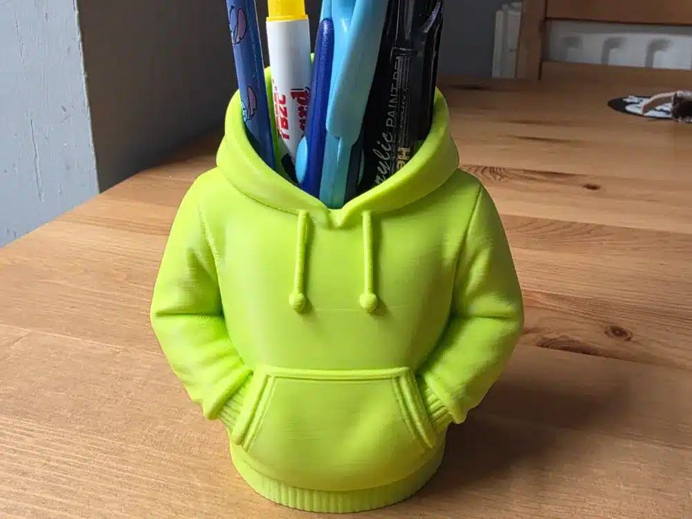 2025-11-12_56954553fa10d8 Bright yellow hoodie-shaped pen holder on a wooden table, filled with colorful pens and markers. Novelty desk organizer. | Sky Rye Design Bright yellow hoodie-shaped pen holder on a wooden table, filled with colorful pens and markers. Novelty desk organizer.