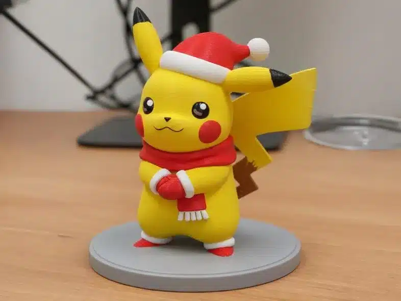 2025-11-12_c0bf6ec4ec783 Festive Pikachu figurine wearing a Santa hat and scarf on a desk, celebrating the holiday season. Cute Christmas decoration. | Sky Rye Design Festive Pikachu figurine wearing a Santa hat and scarf on a desk, celebrating the holiday season. Cute Christmas decoration.