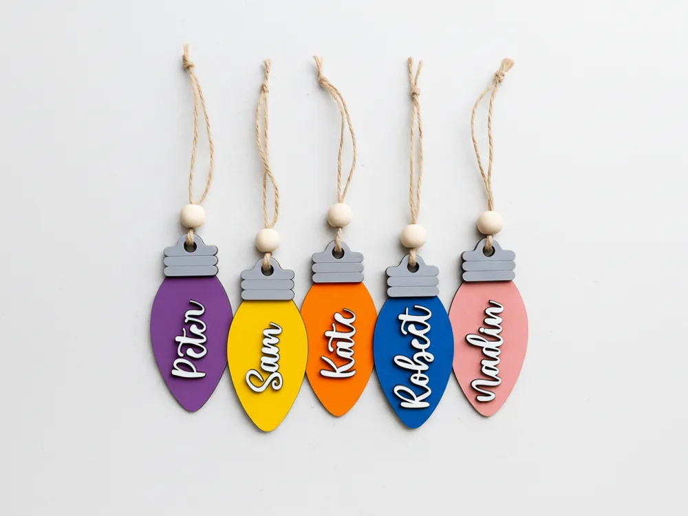 Colorful personalized Christmas light ornaments with names: Peter, Sam, Kate, Robert, and Madlin. Holiday decor with twine and bead accents.