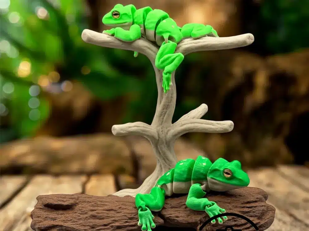 Bright green clay chameleons posed on a miniature tree branch, highlighting their intricate detail and vibrant color against a blurred background.