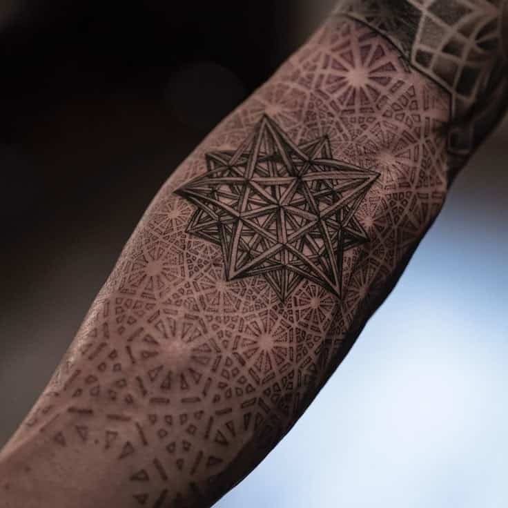 Geometric tattoo with intricate star design on forearm, featuring detailed patterns and shading.