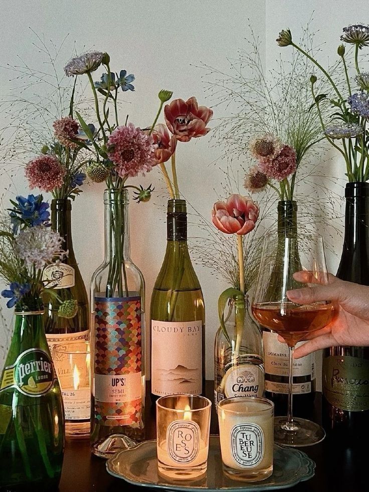 Candles and wildflowers in wine bottles create a cozy atmosphere, with a hand holding a glass of rosé wine. homemade decoration