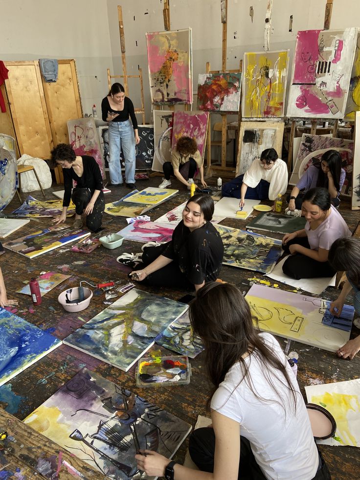 Art students painting on canvases in a creative studio space, surrounded by colorful artworks and supplies.