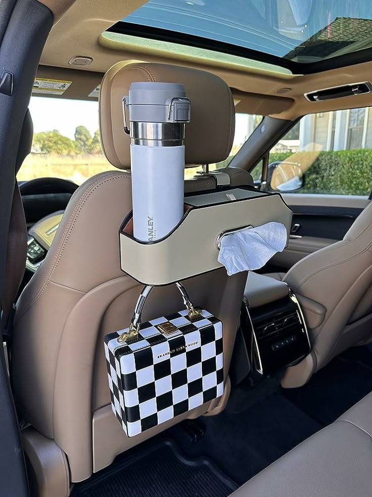 Car backseat organizer with thermos, tissues, and checkered bag for travel convenience and storage.