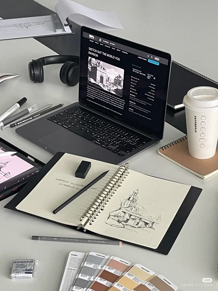 Laptop on a creative desk with sketchbook, pens, color swatches, and coffee, ideal for design and freelance work inspiration.