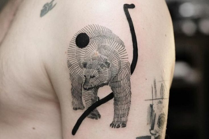 Bear tattoo with abstract black lines on upper arm, featuring intricate shading and design elements.