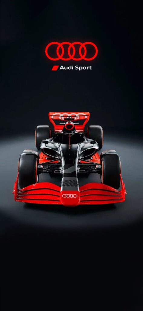Red and black Audi Sport Formula 1 car on display against a dark background, featuring the Audi logo prominently.