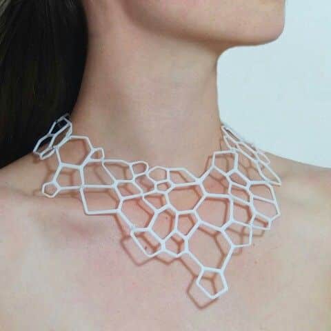 _ 3 Person wearing geometric white necklace with hexagonal design, showcasing modern jewelry on neck and shoulder against a neutral background. | Sky Rye Design Person wearing geometric white necklace with hexagonal design, showcasing modern jewelry on neck and shoulder against a neutral background.