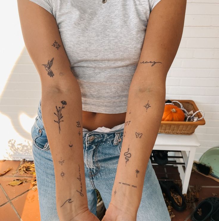 35614f0f-9e5f-4522-be73-77d6169ac465 Close-up of a person with minimalist tattoos on their arms, wearing a grey crop top and jeans, standing in a casually decorated space. | Sky Rye Design Close-up of a person with minimalist tattoos on their arms, wearing a grey crop top and jeans, standing in a casually decorated space.
