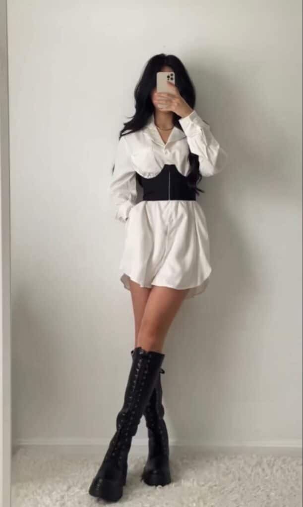 _ 36 Fashion-forward outfit: White shirt dress with black corset belt and knee-high black boots, perfect for a chic, modern look. | Sky Rye Design Fashion-forward outfit: White shirt dress with black corset belt and knee-high black boots, perfect for a chic, modern look.