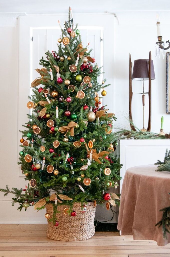 _ 38 Festive Christmas tree adorned with colorful baubles and dried orange slices in a cozy living room setting. | Sky Rye Design Festive Christmas tree adorned with colorful baubles and dried orange slices in a cozy living room setting.