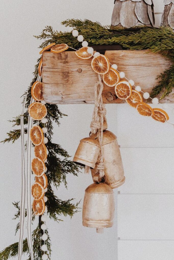 _ 39 Rustic holiday decor with dried orange slices, evergreen branches, and vintage bells on wooden mantle. | Sky Rye Design Rustic holiday decor with dried orange slices, evergreen branches, and vintage bells on wooden mantle.