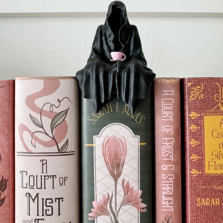 3D Printed Bookshelf Suriel _ Ghost _ Grim Reaper Figurine - with Teacup Attached Hooded figure sipping tea over Sarah J. Maas books on a shelf, including A Court of Mist and Fury and A Court of Frost and Starlight. | Sky Rye Design Hooded figure sipping tea over Sarah J. Maas books on a shelf, including A Court of Mist and Fury and A Court of Frost and Starlight.