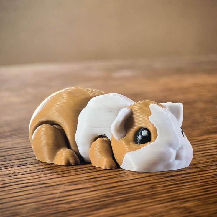 Cute 3D-printed guinea pig figurine with brown and white colors on a wooden surface, showcasing handmade craftsmanship.