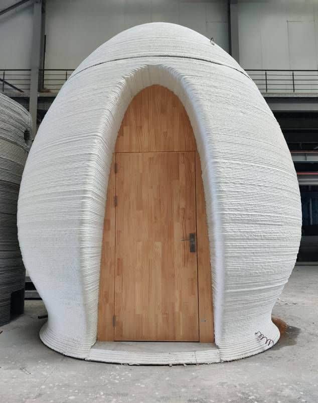 3d printed construction by WINSUN 3D-printed egg-shaped house with wooden door, showcasing innovative architecture and sustainable building technology. | Sky Rye Design 3D-printed egg-shaped house with wooden door, showcasing innovative architecture and sustainable building technology.