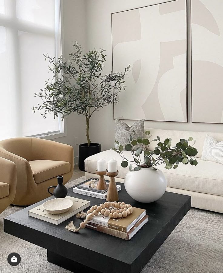 Modern living room with beige sofa, abstract art, wooden coffee table, decorative plants, candles, and books for a minimalist aesthetic.