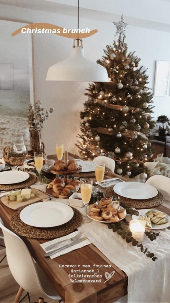Festive Christmas brunch setup with elegant tableware, delicious pastries, and a beautifully decorated Christmas tree in the background.