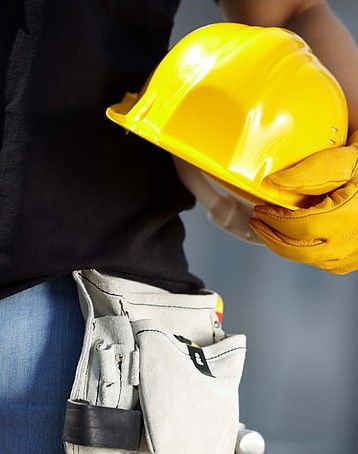 _ 4 Construction worker holding a yellow hard hat and wearing a tool belt, symbolizing safety and readiness on site. | Sky Rye Design Construction worker holding a yellow hard hat and wearing a tool belt, symbolizing safety and readiness on site.