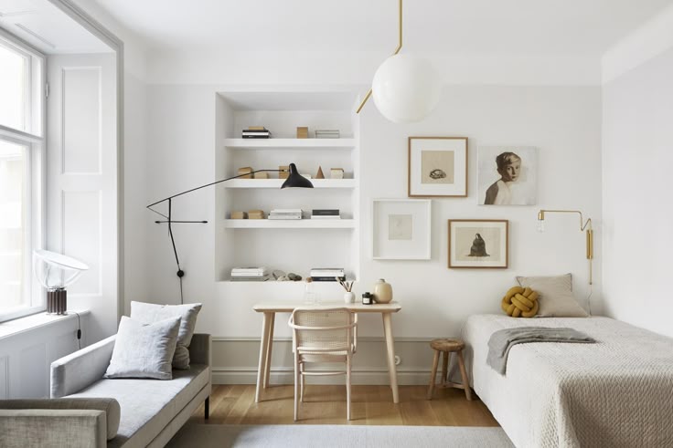 Minimalist cozy bedroom with natural light, featuring a bed, wooden desk, modern wall shelves, and art decor.