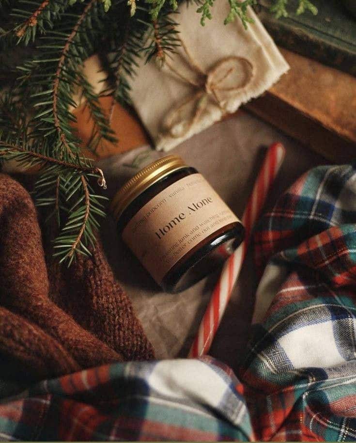 _ 43 Cozy holiday scene with a Home Alone candle, candy cane, pine branches, and plaid scarf for a warm, festive atmosphere. | Sky Rye Design Cozy holiday scene with a Home Alone candle, candy cane, pine branches, and plaid scarf for a warm, festive atmosphere.