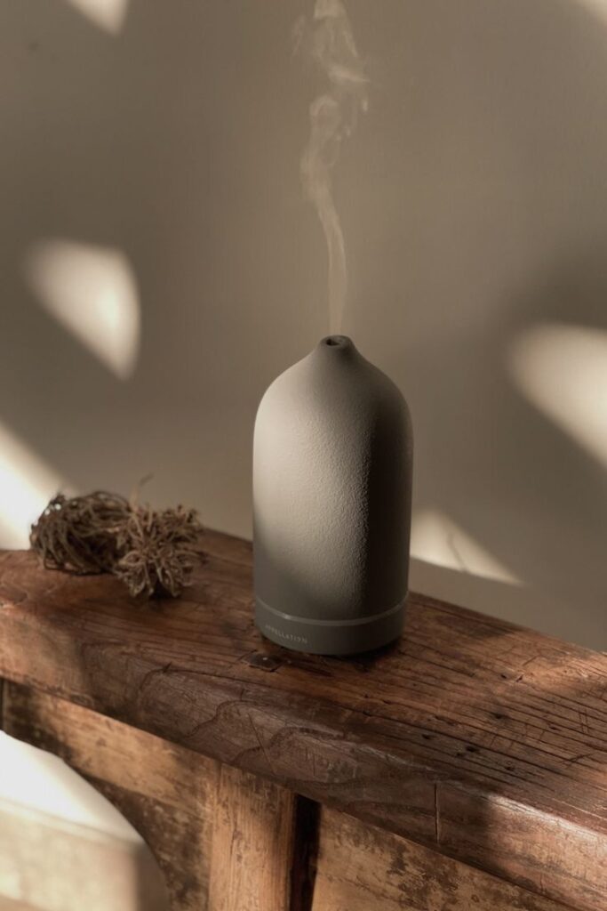 _ 45 Ceramic essential oil diffuser releasing steam on rustic wooden surface, creating a calming ambiance with soft lighting and shadows. | Sky Rye Design Ceramic essential oil diffuser releasing steam on rustic wooden surface, creating a calming ambiance with soft lighting and shadows.