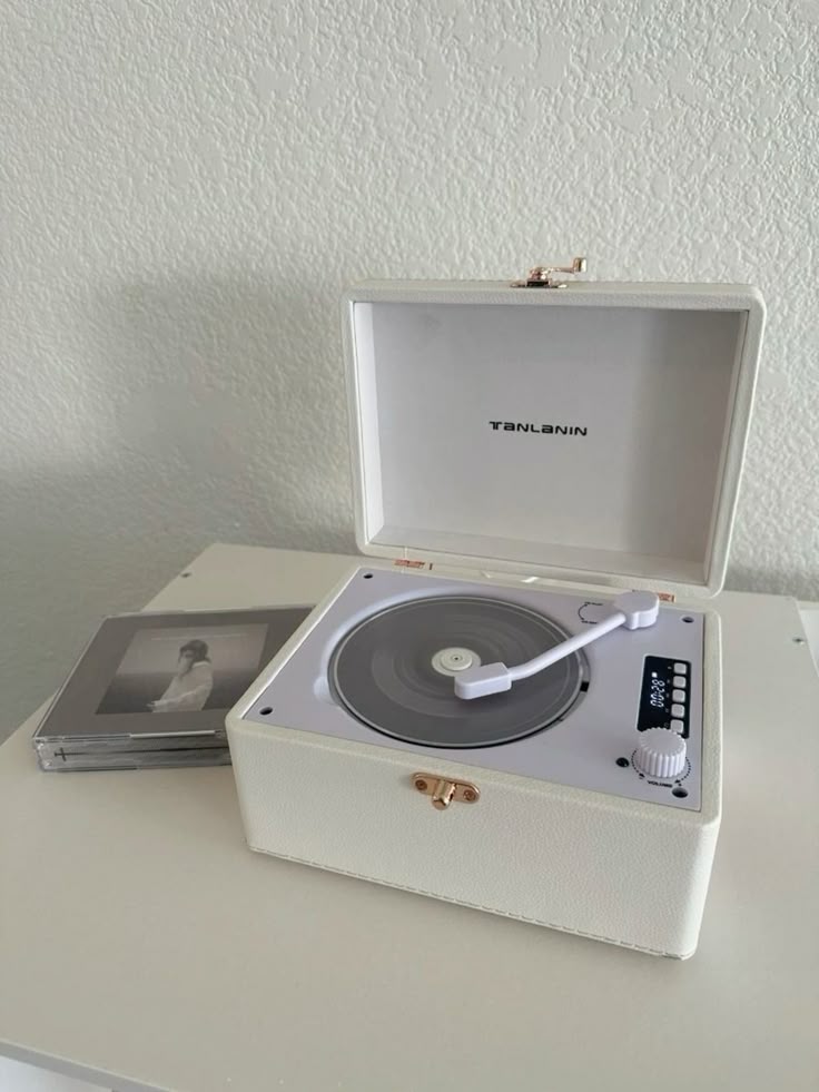 _ 48 White vintage record player with a CD next to it on a table, offering a classic and retro music setup for audiophiles. | Sky Rye Design White vintage record player with a CD next to it on a table, offering a classic and retro music setup for audiophiles.