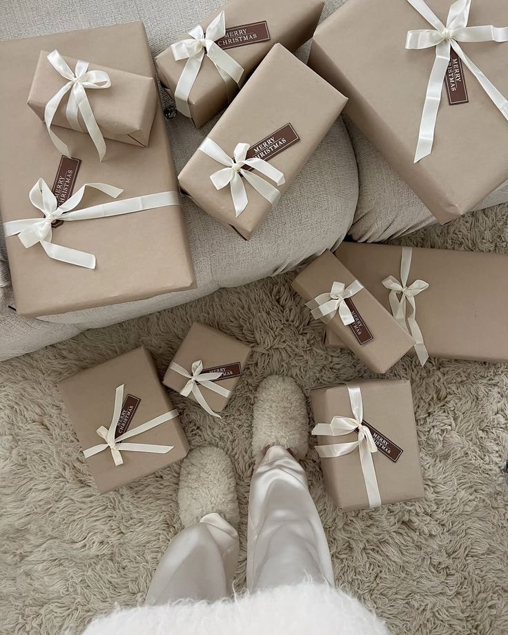 Cozy Christmas gifts wrapped in brown paper with white ribbons on a fluffy rug, viewed from above.