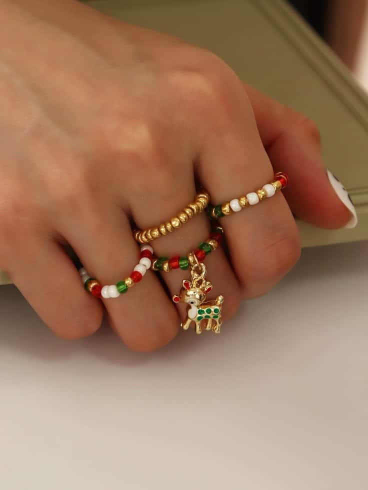 4pcs Christmas Elk Charm Ring Close-up of a hand wearing colorful beaded rings with gold accents and a reindeer charm, showcasing unique festive jewelry design. | Sky Rye Design Close-up of a hand wearing colorful beaded rings with gold accents and a reindeer charm, showcasing unique festive jewelry design.