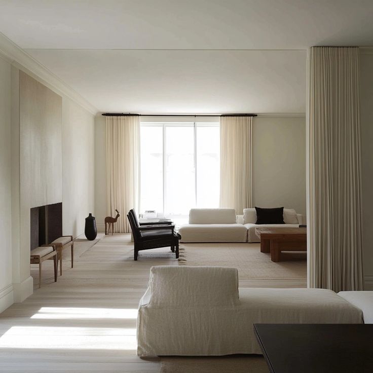 Modern minimalist living room with neutral tones, white sofas, large window, and soft ambient lighting.