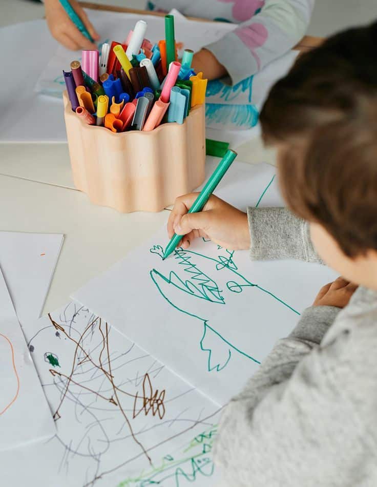 _ 5 Children drawing colorful pictures with markers, showcasing creativity and art skills on paper at a table. | Sky Rye Design Children drawing colorful pictures with markers, showcasing creativity and art skills on paper at a table.