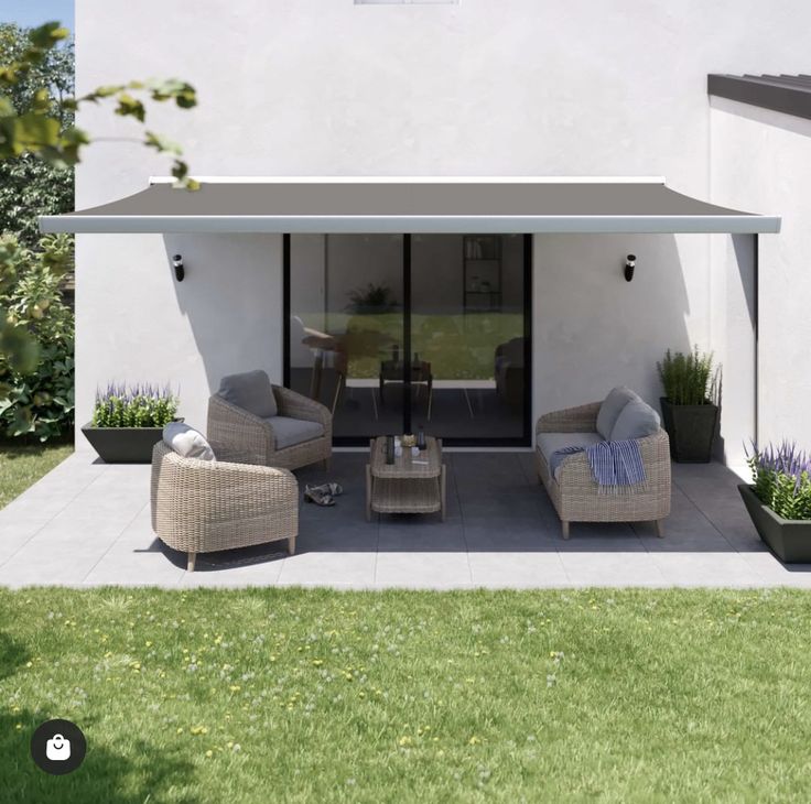 Outdoor patio with wicker furniture, awning, and potted plants. Cozy seating area on tiled flooring, perfect for relaxation and gatherings.