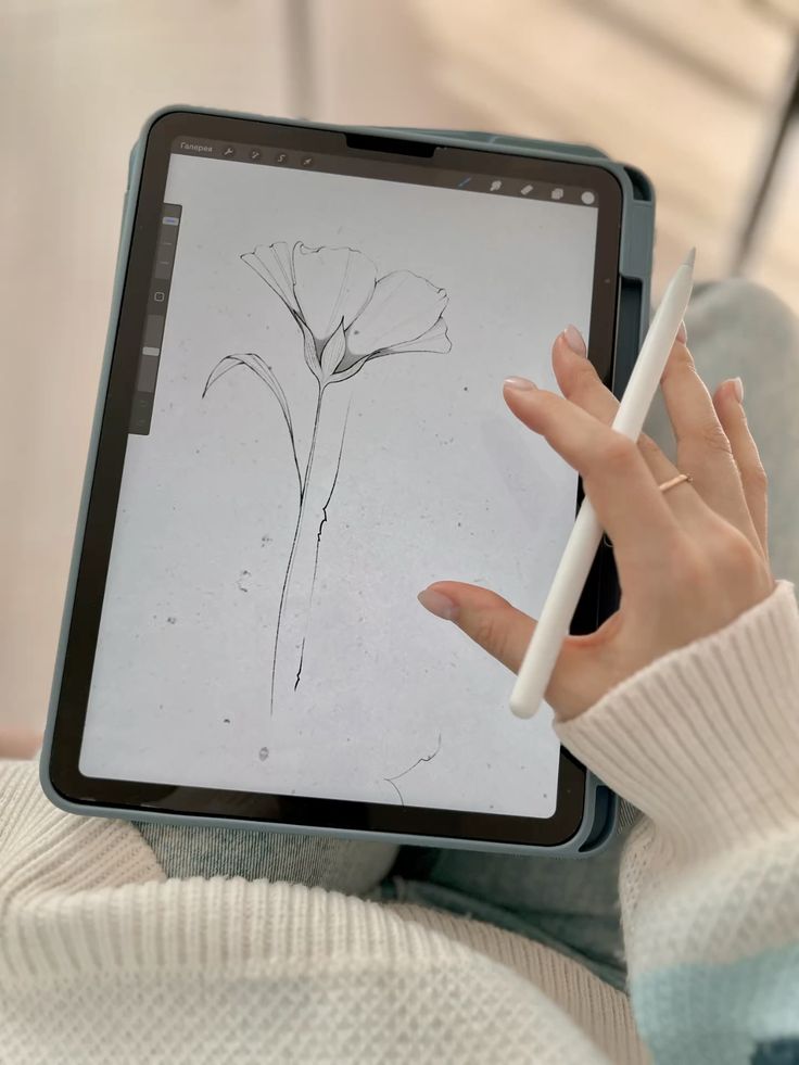 5371d25584aba88d805dabee5e74da79 Person sketching a flower on a digital tablet with a stylus, wearing a cozy white and pastel striped sweater. | Sky Rye Design Person sketching a flower on a digital tablet with a stylus, wearing a cozy white and pastel striped sweater.