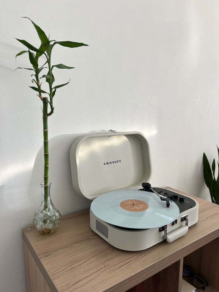 _ 54 Vintage Crosley record player on wooden table with spinning vinyl, beside a bamboo plant in a glass vase. Minimalist home decor. | Sky Rye Design Vintage Crosley record player on wooden table with spinning vinyl, beside a bamboo plant in a glass vase. Minimalist home decor.