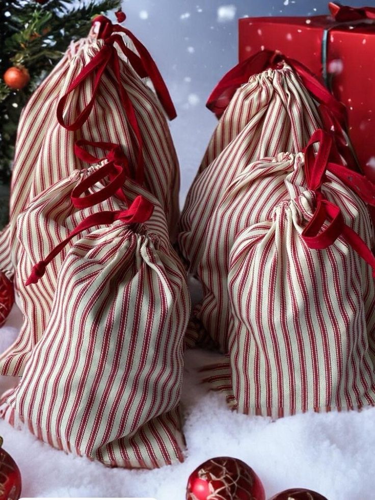 _ 55 Festive striped gift bags with red ribbons under a Christmas tree surrounded by snow and ornaments, perfect for holiday celebrations. | Sky Rye Design Festive striped gift bags with red ribbons under a Christmas tree surrounded by snow and ornaments, perfect for holiday celebrations.