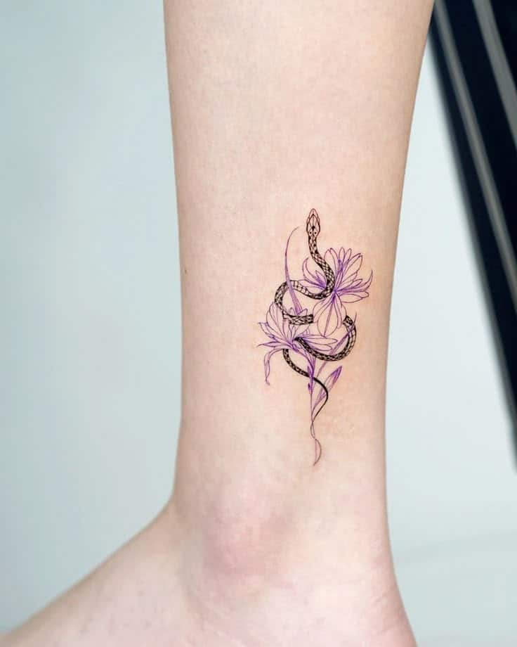 Intricate snake and flower ankle tattoo with purple accents, showcasing a unique blend of nature and art on delicate skin.