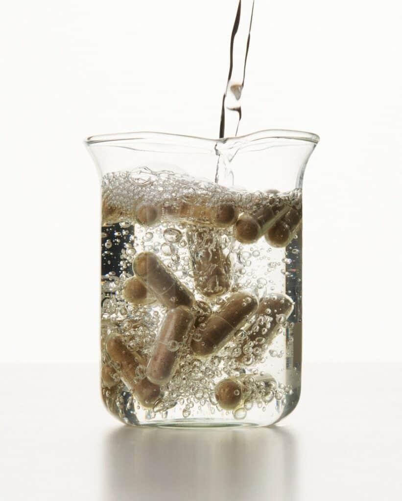 5c6d5a78fc97b567b7da189d375b6427 Clear beaker with bubbling water and dissolving capsules, highlighting supplement absorption process. | Sky Rye Design Clear beaker with bubbling water and dissolving capsules, highlighting supplement absorption process.